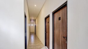 Un pasillo con dos puertas de madera, suelo de baldosas e iluminación empotrada en el techo.
