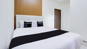 Una habitación de hotel con una cama, un panel de pared de madera, una puerta y un interruptor de luz.