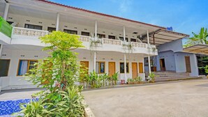 A hotel with a covered outdoor area, multiple balconies, and a pool.