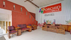 A reception area with a red brick wall, wooden furniture, and a banner for Orchid Villa.