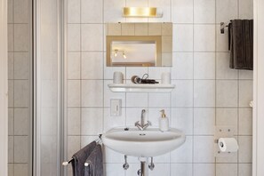 Une salle de bain avec un lavabo, un miroir, un porte-serviettes et une serviette accrochée au mur.