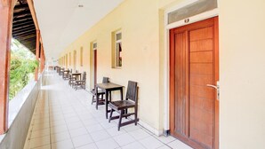 A corridor with tables and chairs, wooden doors, and a tiled floor.