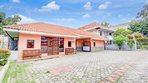A building with a tiled roof, a paved courtyard, and a bench.