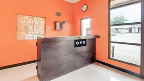 A reception desk with a sign reading 'OYO,' a clock, and a window with a view of the street.