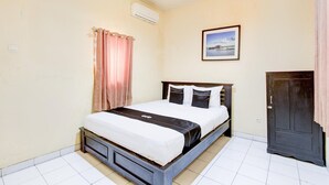 A bedroom with a bed, a wardrobe, a picture on the wall, and an air conditioning unit.