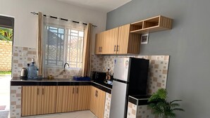 Eine Küche mit Holzausbau, einem schwarzen Kühlschrank, einer Spüle und einem Fenster mit Vorhängen.