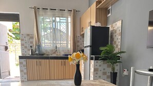 Eine moderne Küche mit Holzausstattung, einem Esstisch und einem Topf mit Pflanze.