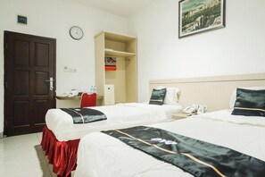 Habitació d'hotel amb dos llits, un armari, un escriptori amb cadira, un rellotge i un quadre al mur.