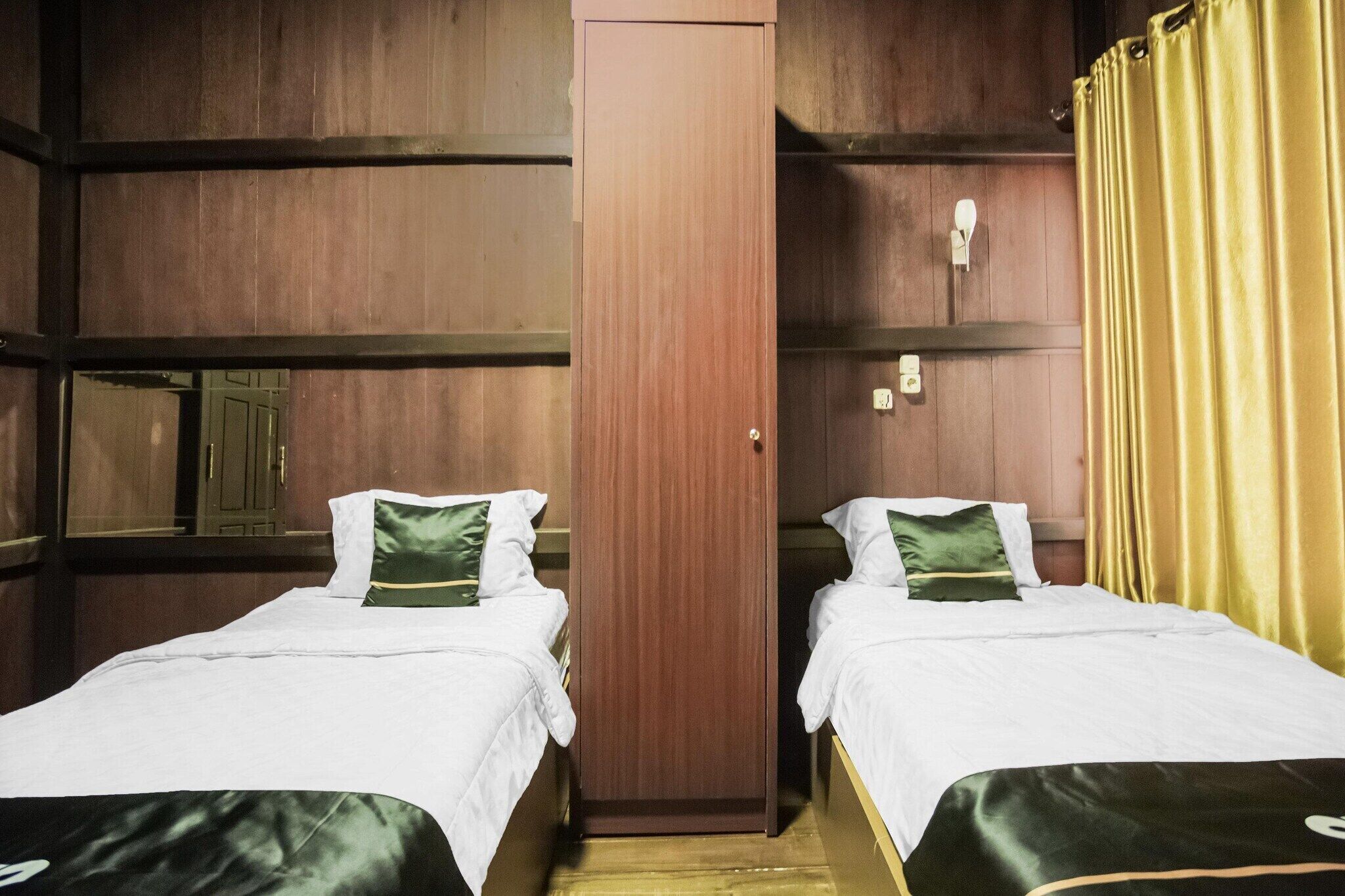 A room with two beds, a wooden wardrobe, and a yellow curtain.