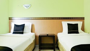 Una habitación con dos camas, una mesita de noche y un aplique en la pared.