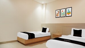 A hotel room with two beds, a nightstand, and three framed artworks on the wall. - Luxury Twin Stay with Free WiFi and Parking (Palembang)