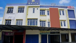Un edifici de diversos pisos amb un cartell de 'MALEO' i 'Giri Studio' a la planta baixa, i un cartell de 'MALEO Laundry' al segon pis.
