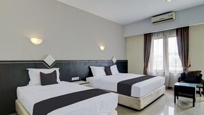 Camera d'albergo con due letti, un comodino, una sedia e un condizionatore d'aria.