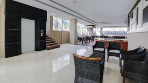 A spacious indoor area with a dining area, a staircase, and a kitchen in the background.