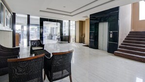 A spacious lobby with a glass wall, a reception desk, and a staircase.