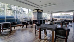A spacious indoor area with multiple tables and chairs, large windows, and a central air conditioning unit.