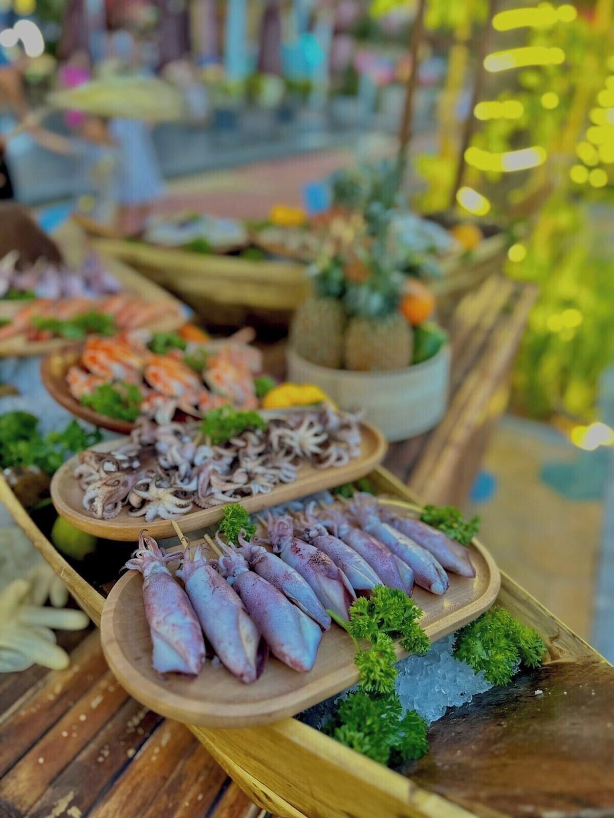 A seafood display with various dishes, including squid and shrimp, arranged on wooden platters.