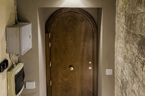 Eine Holztür mit Messingklinke, ein an der Wand befestigtes Stromdosenfeld und ein Thermostat.