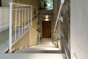 Eine schmale Treppe mit weißer Geländer, eine Holztür am Fuß und ein an der Wand befestigtes Telefon.