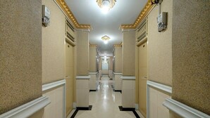 Ein Korridor mit Fliesenboden, weißen Wänden und einer Decke mit einer Leuchte.