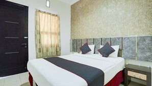 Quarto de hotel com cama, mesa de cabeceira, porta e janela com cortinas.