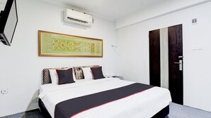 Quarto de hotel com cama, ar-condicionado fixado na parede, obra de arte emoldurada, guarda-roupa e porta.