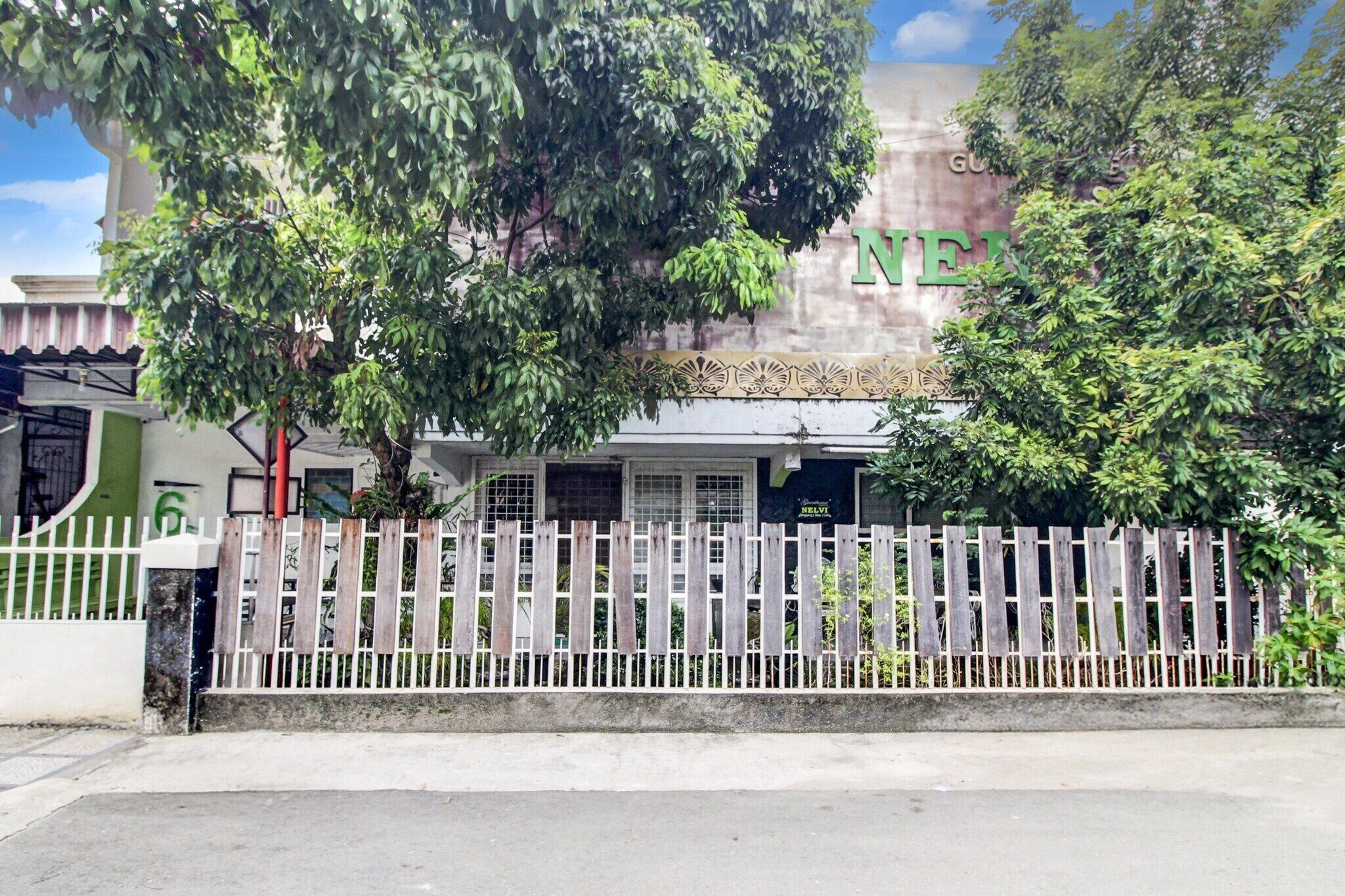 A building with a sign that reads 'NEE' and a white picket fence in front.