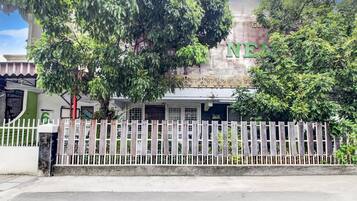 A building with a sign that reads 'NEE' and a white picket fence in front.