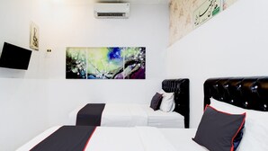 Quarto de hotel com duas camas, televisão de tela plana e arte abstrata nas paredes.