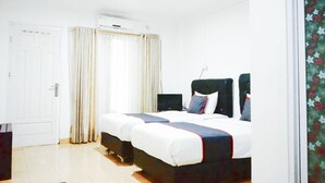 Une chambre à coucher avec un lit, des rideaux, un appareil de climatisation et une porte.