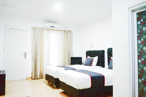 A bedroom with a bed, curtains, an air conditioning unit, and a door.