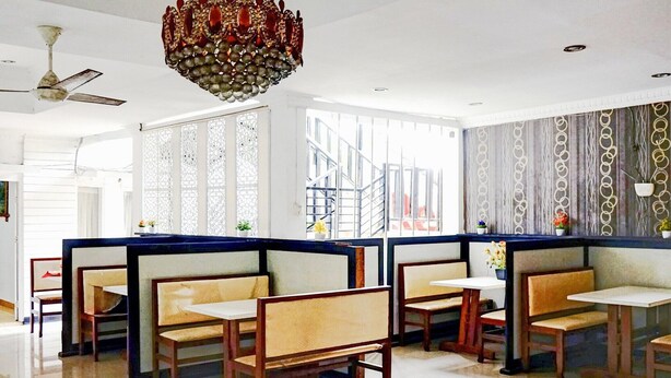 Un restaurant avec des banquettes, un lustre et une vue sur un bâtiment à l’extérieur.