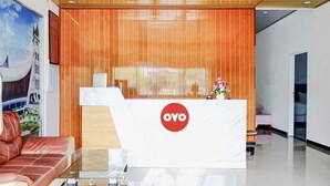 Un comptoir d’accueil avec un logo, un mur recouvert de panneaux en bois, un canapé et une table en verre.