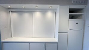 Una cocina compacta con muebles empotrados, un refrigerador y una encimera.