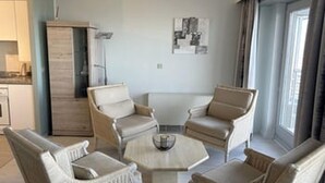 Una habitación de hotel con comedor, un conjunto de sofás y un ventanal grande.