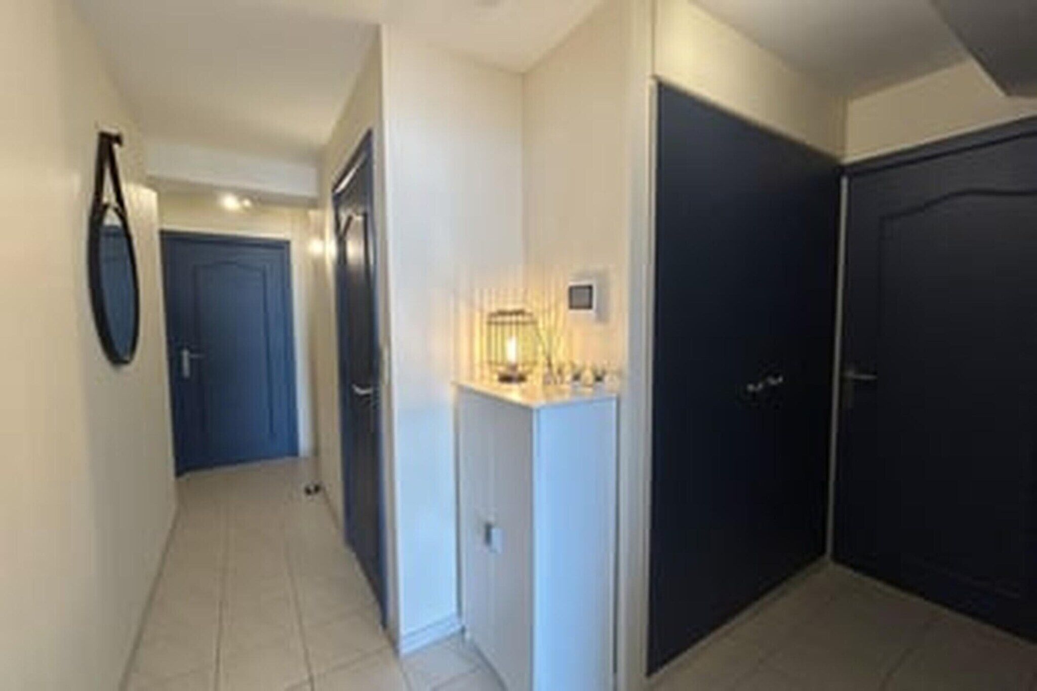 A hallway with a door, a light fixture, and a wall-mounted object.