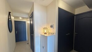 Un pasillo con una puerta, un accesorio de iluminación y un objeto fijado a la pared.