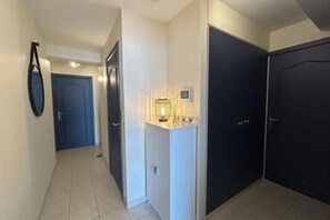 A hallway with a door, a light fixture, and a wall-mounted object.