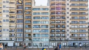 En flervåningsbyggnad med bostäder, balkonger, en central innergård och en flaggstång.