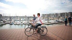 Un port esportiu amb vaixells, un ciclista i un camí per a vianants.