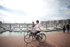Ein Yachthafen mit Booten, einem Radfahrer und einem Fußweg.