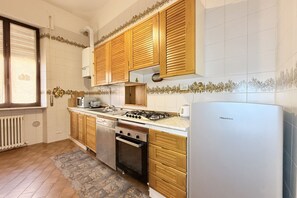 A kitchen with wooden cabinets, a gas stove, a dishwasher, and a refrigerator.