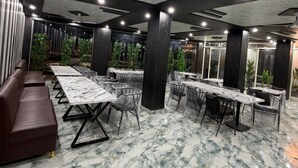 Ein Konferenzraum mit Marmorboden, dunklen Holzsäulen und Deckenventilatoren.