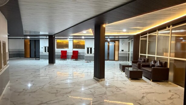 Eine großzügige Lobby mit Marmorböden, roten Stühlen, Sofas und einem modernen Deckenstil.