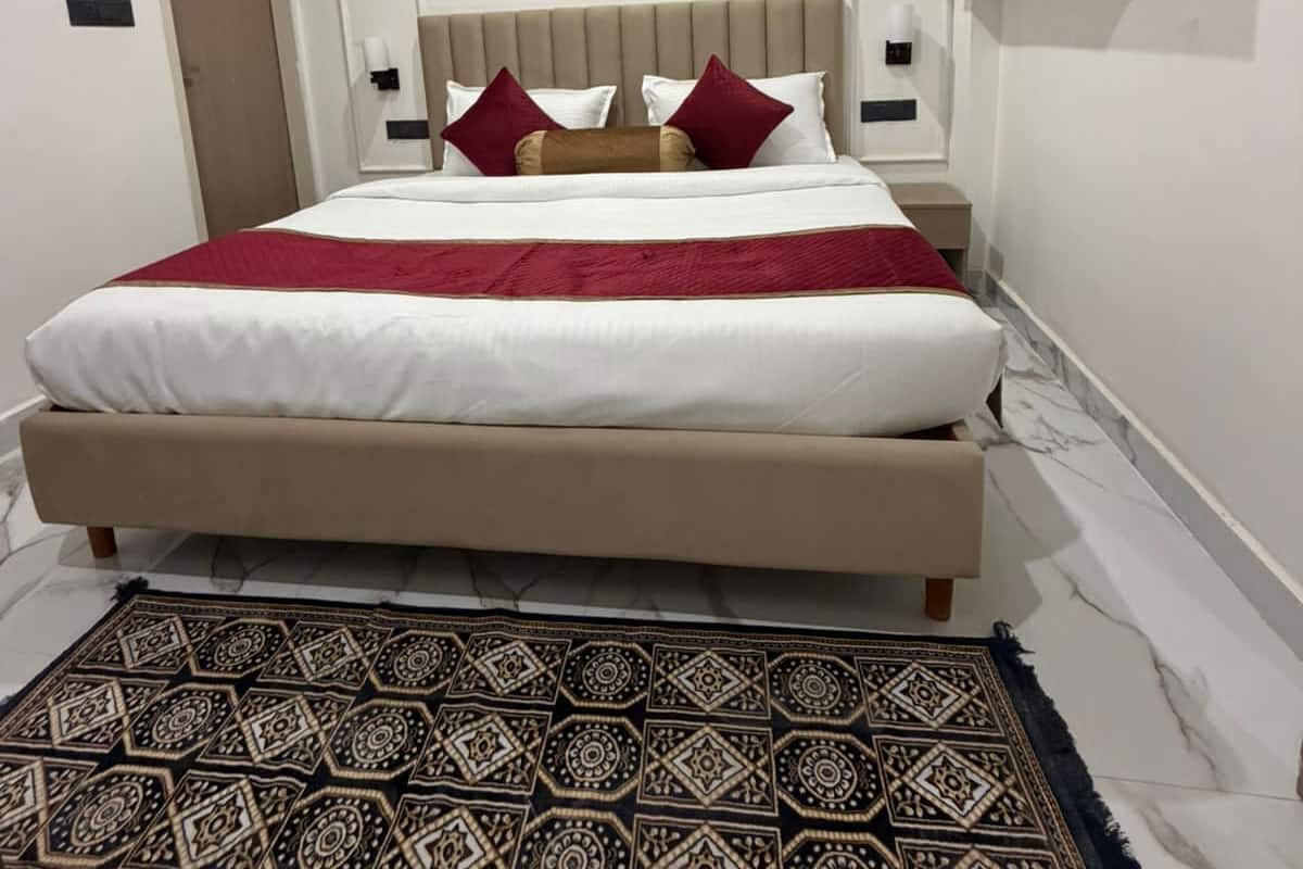 Ein Schlafzimmer mit einem Bett, Nachttischen, einem Kopfteil, einem Wandcabinet und einem gemusterten Teppich.