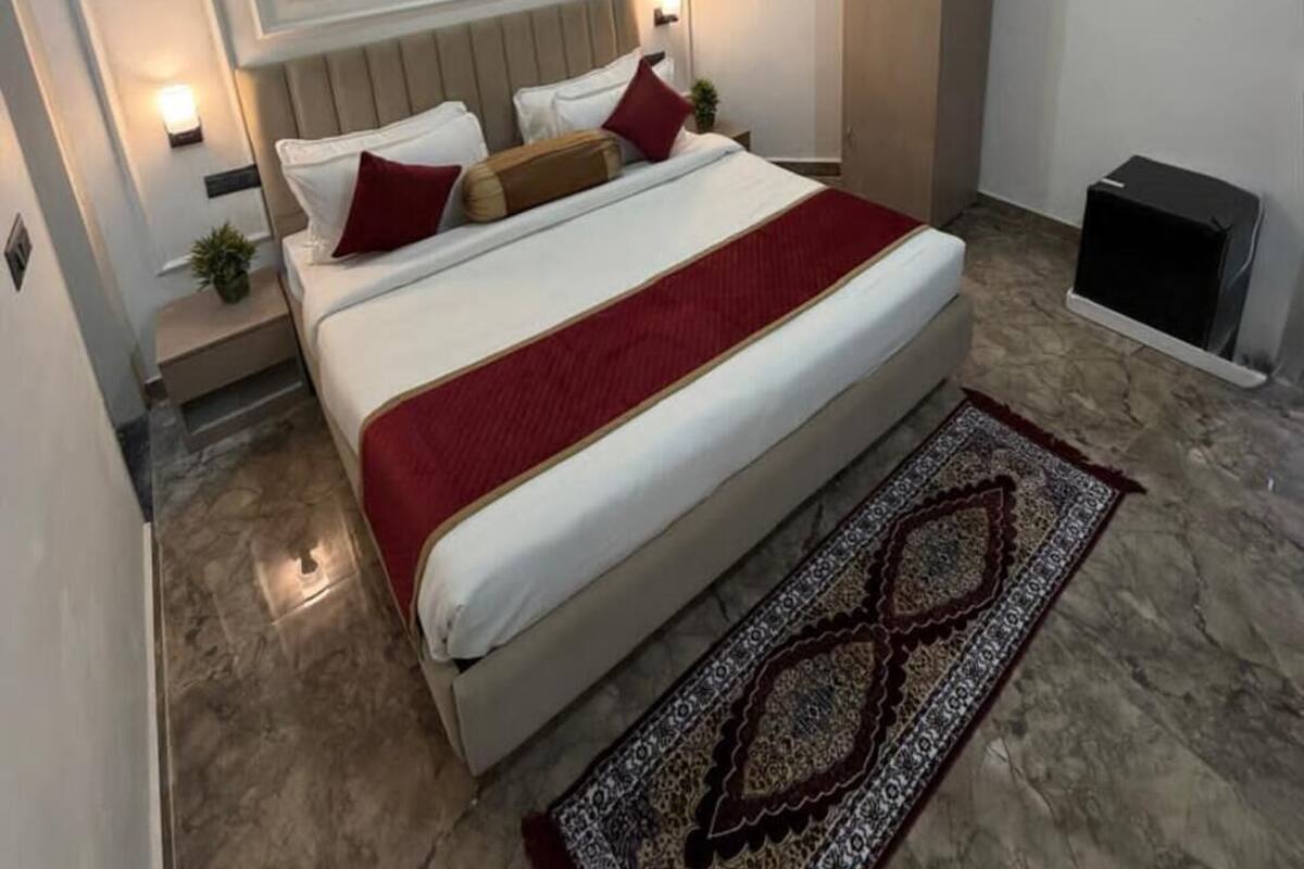 Una habitación de hotel moderna con cama, ventilador de techo, mesita de noche, armario y alfombra estampada.