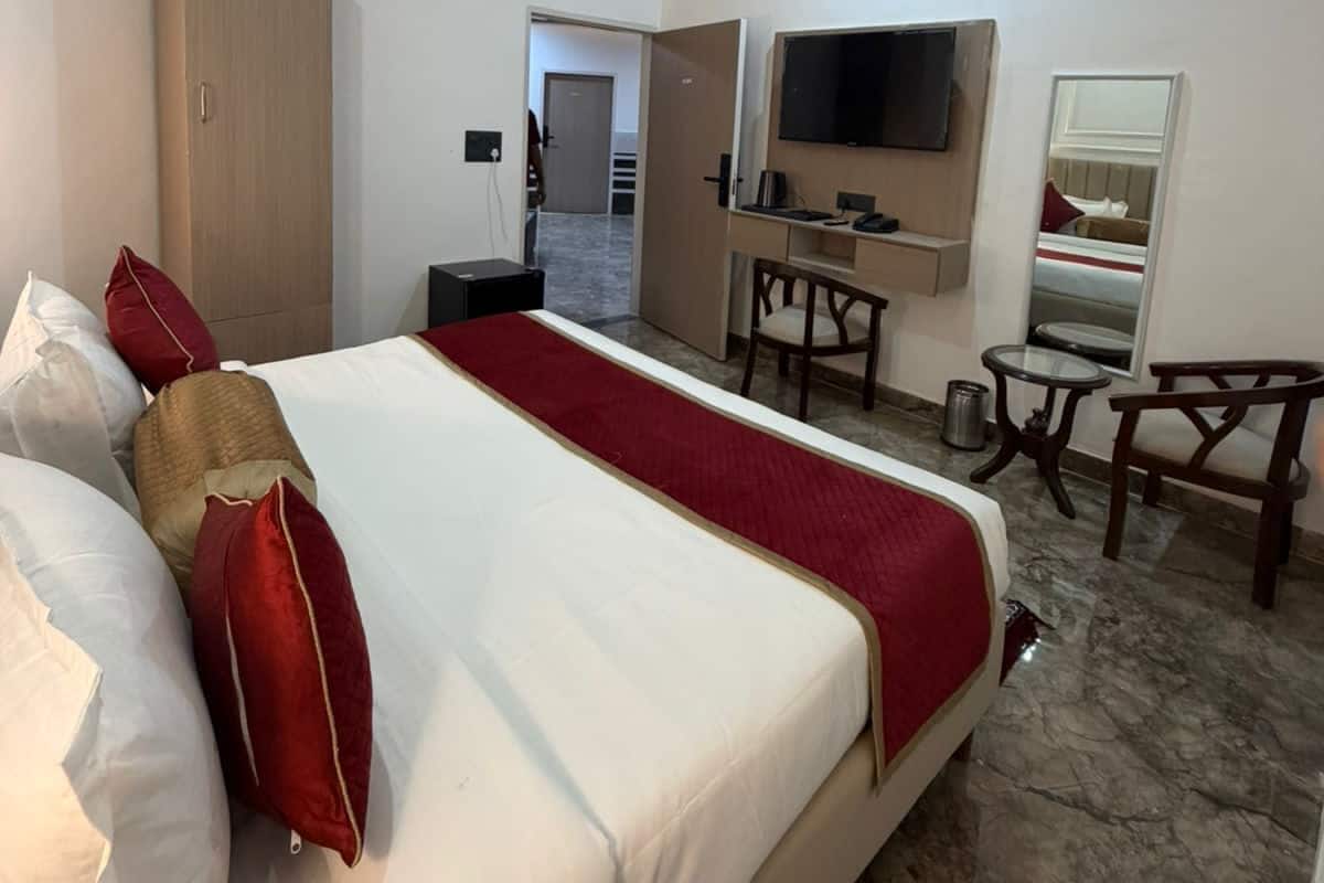 Ein Hotelzimmer mit Bett, Schreibtisch, Stuhl, Fernseher und Deckenventilator.