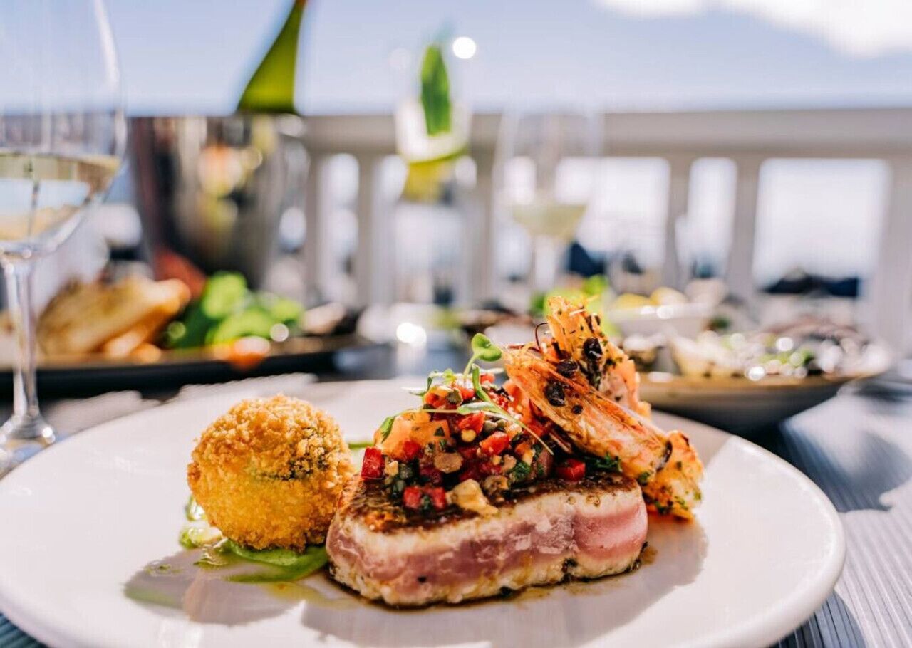 Un plat composé de fruits de mer, une portion de pain pané de forme ronde et une garniture, le tout présenté sur une assiette blanche.
