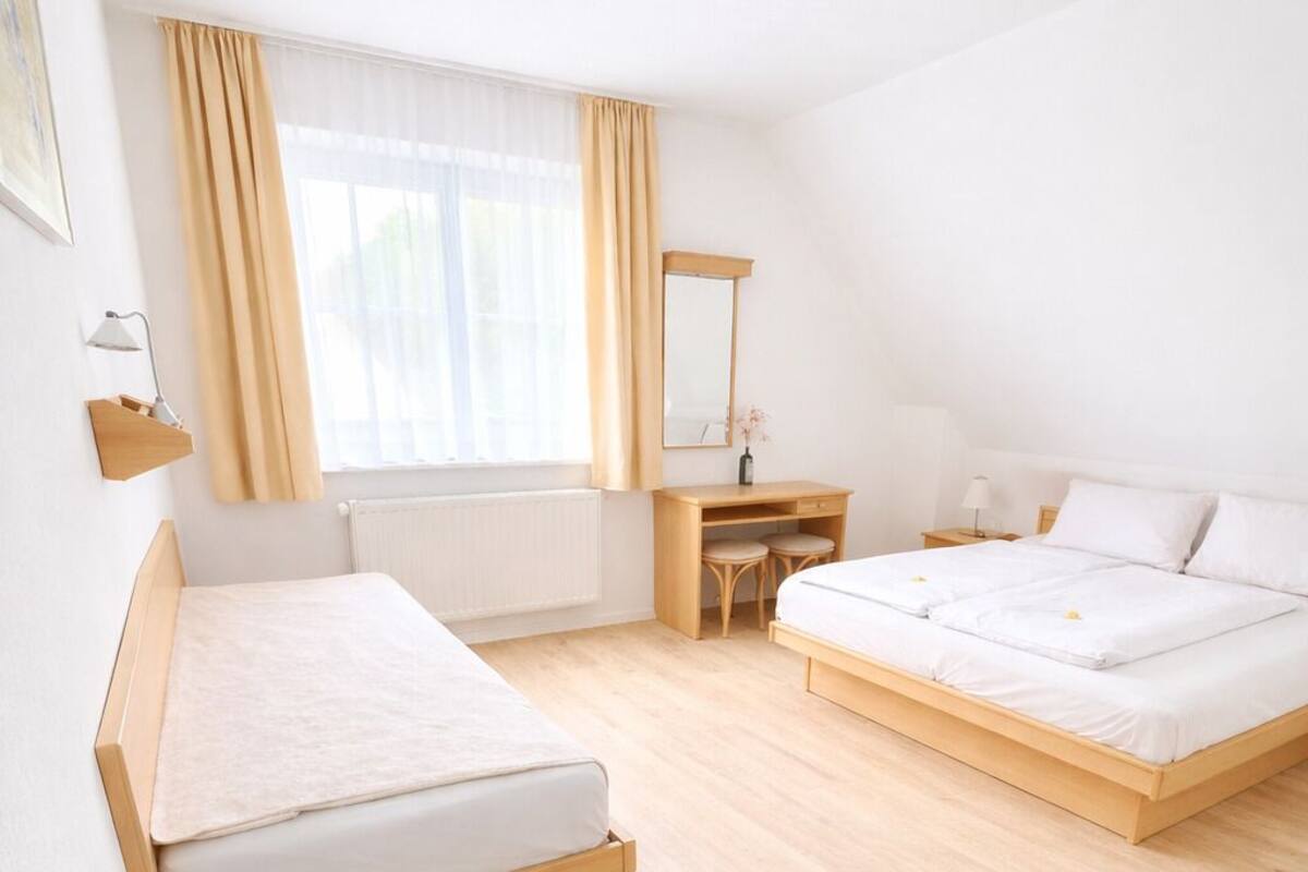 A modern hotel room with two beds, a desk, and a large window with curtains.
