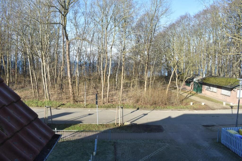A parking area with a building in the background, surrounded by trees.
